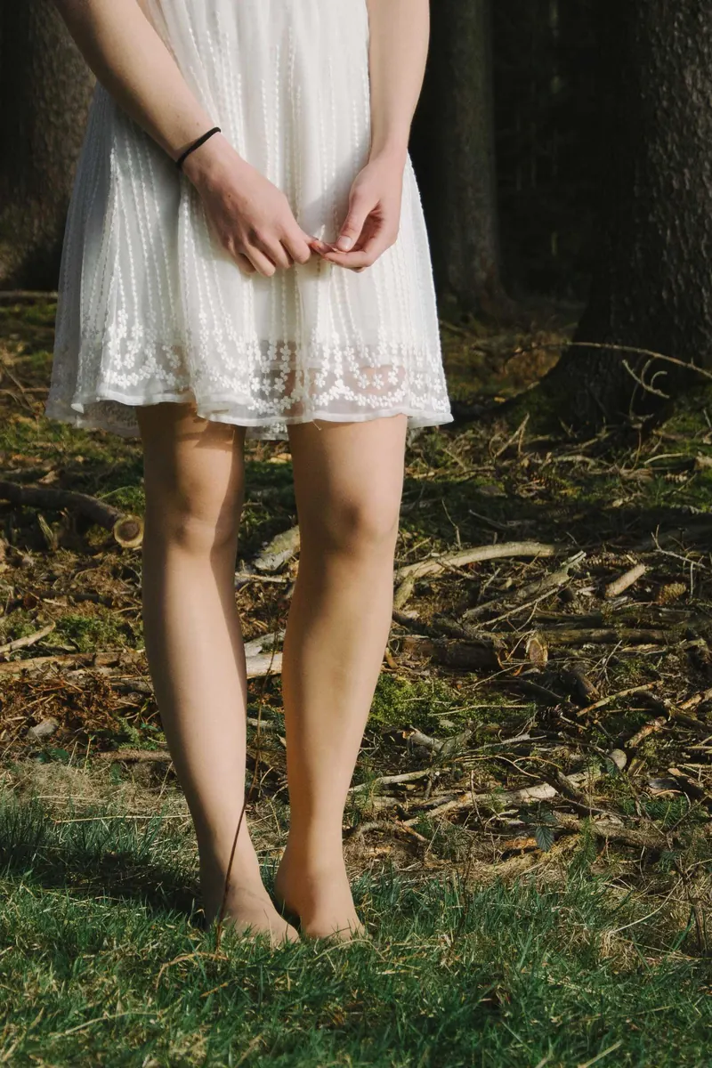 Vestido branco e pés descalços na grama